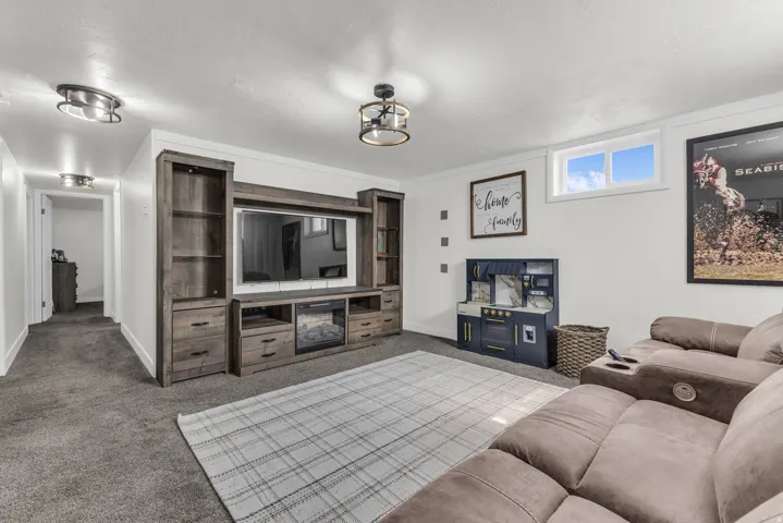 Entertainment area featuring a built-in media center with shelving and storage, an electric fireplace, recessed lighting, and a window with white trim