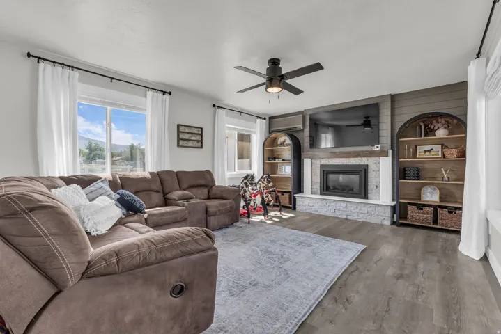 Spacious living area featuring wood-finish flooring, a ceiling fan, and large windows with mountain scenery