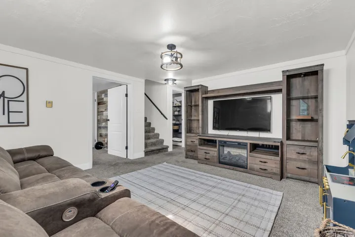 Living area featuring a custom wood-finish entertainment center with integrated electric fireplace, built-in shelving, carpet flooring, and white trim