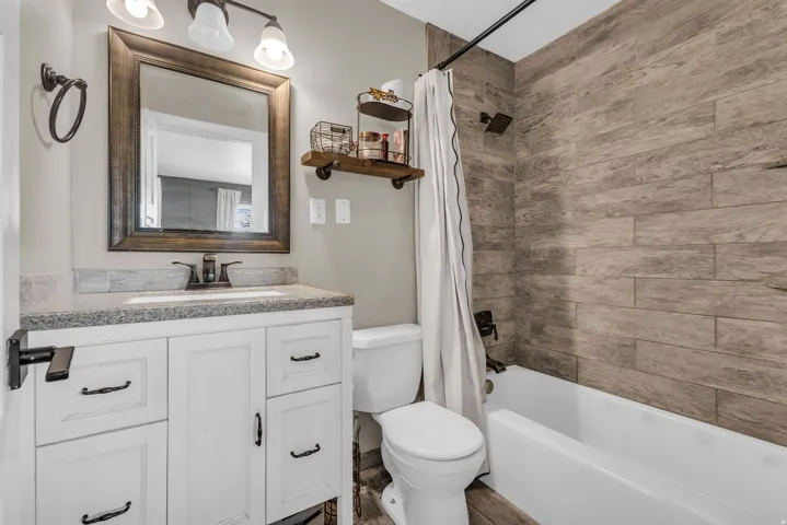 Bathroom featuring a white shaker-style vanity with a speckled countertop and integrated sink