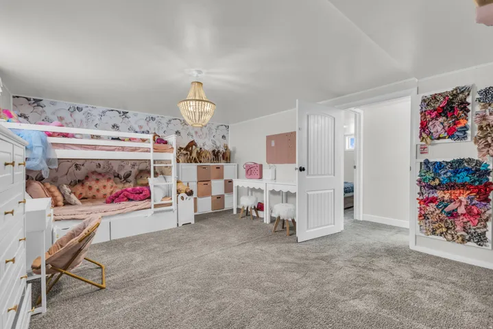 Spacious room featuring gray carpet flooring and white walls with an accent wall of floral wallpaper