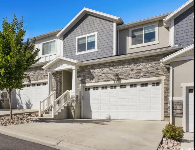 Townhome exterior featuring stacked stone, horizontal siding, and shake siding accents