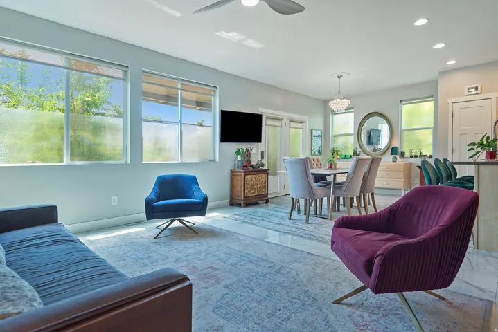 Bright living area featuring large windows with roller shades, recessed lighting, and a ceiling fan