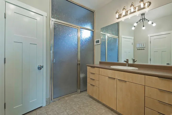 Bathroom featuring a long wood-finish vanity with an integrated sink, a large mirror, and a multi-bulb light fixture