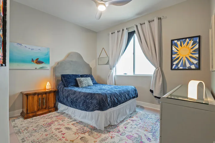 Bedroom featuring light gray walls, wood-finish flooring, a contemporary ceiling fan, and a large window with privacy blinds