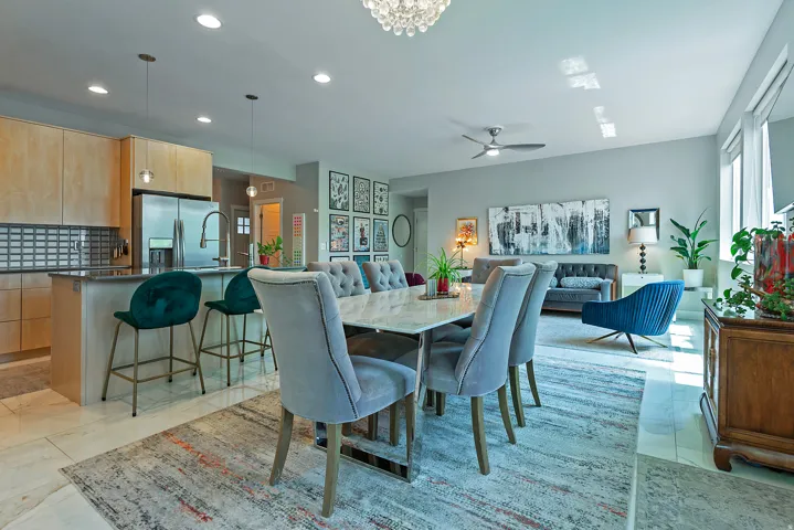 Open-concept living area featuring a kitchen with light wood-finish cabinetry, stainless steel refrigerator, and a dark countertop island with seating