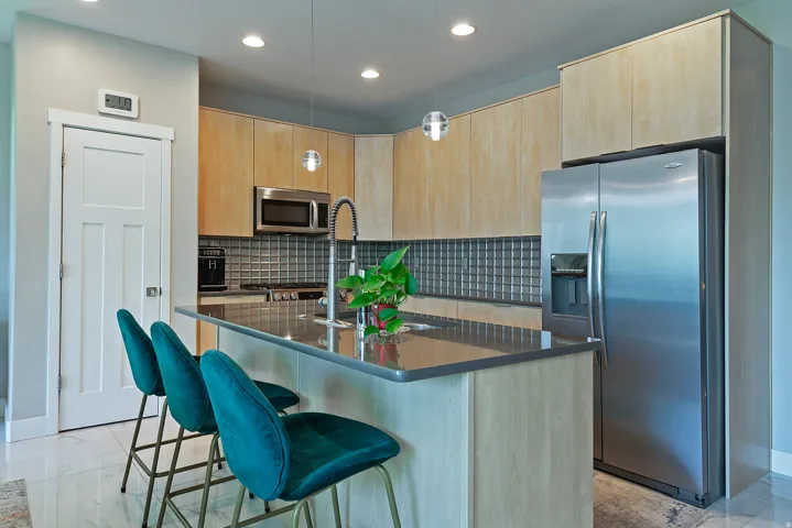 Kitchen featuring light wood-finish cabinetry and a complementary dark countertop island with an integrated sink and gooseneck faucet