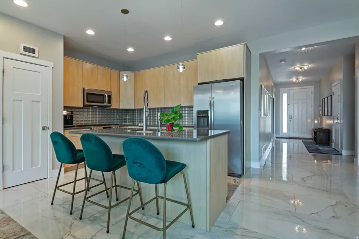 Modern kitchen featuring light wood-finish cabinetry, stainless steel appliances, and a tiled backsplash