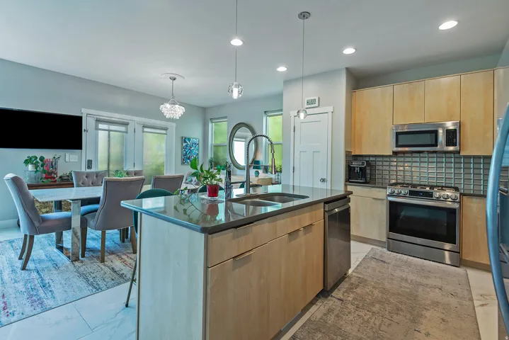 Kitchen island featuring an undermount sink, gooseneck faucet, and pendant lighting