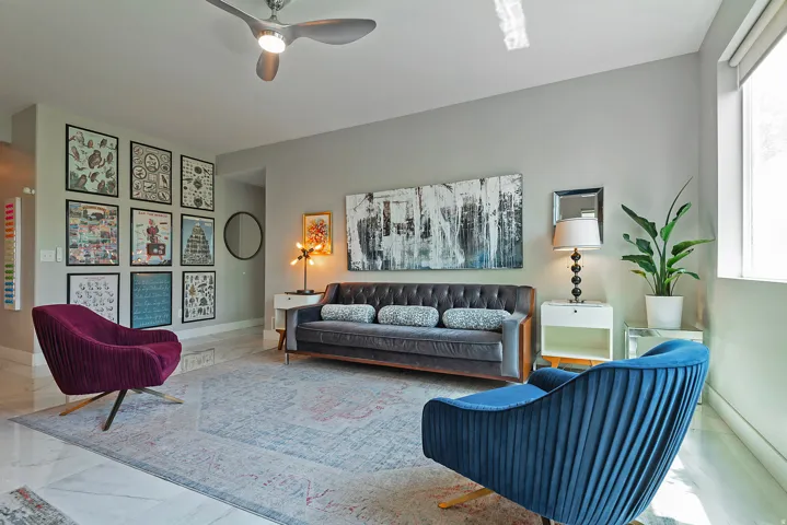 Spacious living area featuring light-toned walls and large format tile flooring