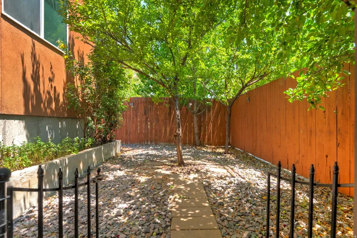 Enclosed yard area featuring multiple mature fruit trees providing natural canopy, and a lock out fence separating the yard