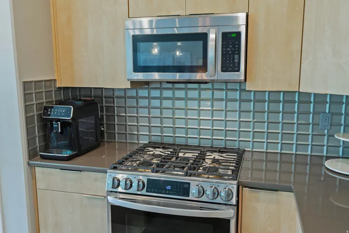 Kitchen featuring stainless steel appliances, flat-panel cabinetry, a gas range, and a dimensional tiled backsplash