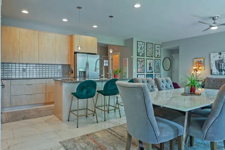 Open-concept kitchen and dining area featuring light wood cabinetry and a mosaic tile backsplash
