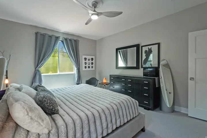 Neutral-toned bedroom featuring a contemporary ceiling fan with integrated lighting