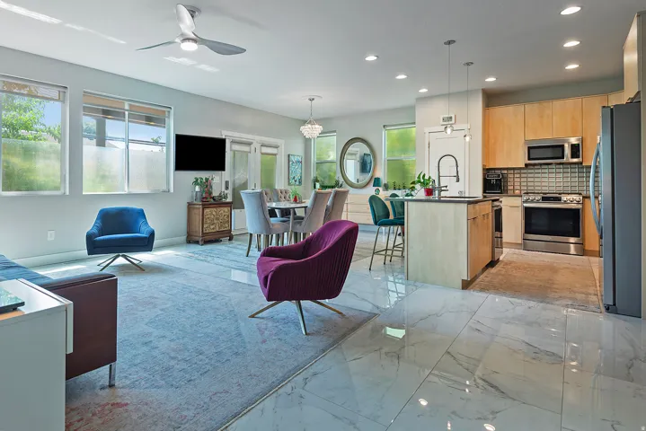 Open-concept living space featuring wood-finish cabinetry, stainless steel appliances, and a kitchen island with seating
