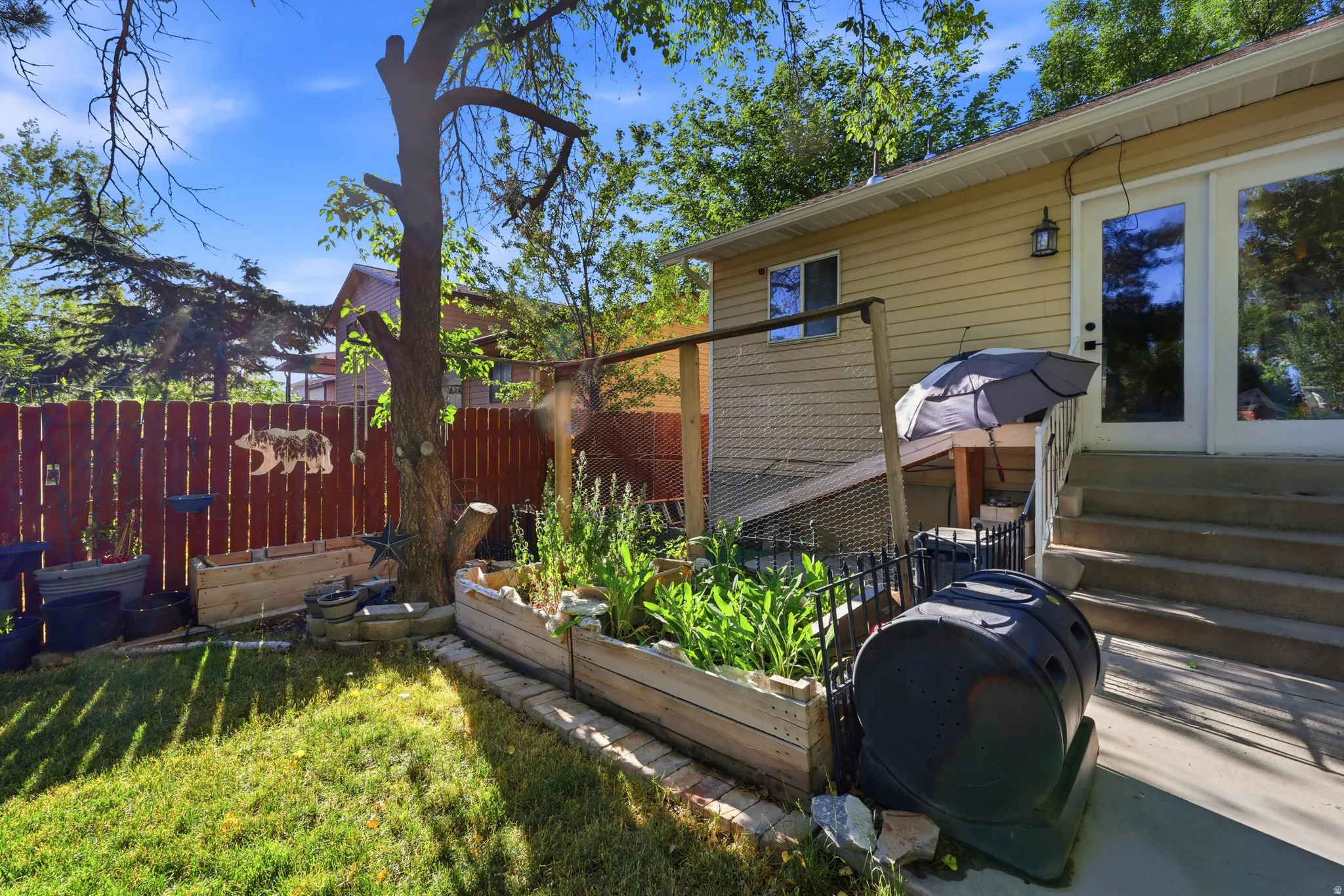 Expansive backyard featuring a wood privacy fence, established trees, and raised garden beds