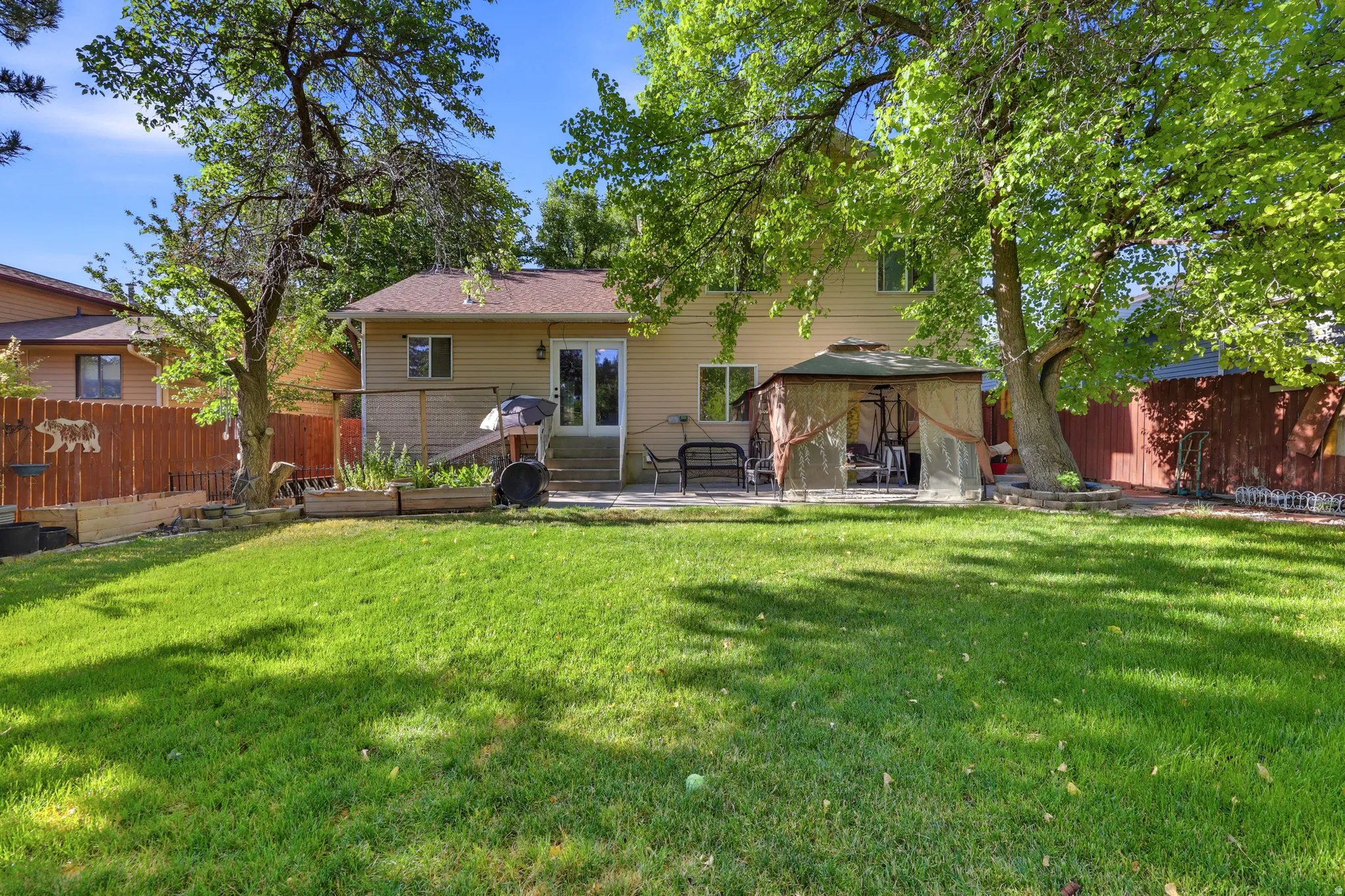 Expansive grassy backyard featuring mature trees providing natural shading