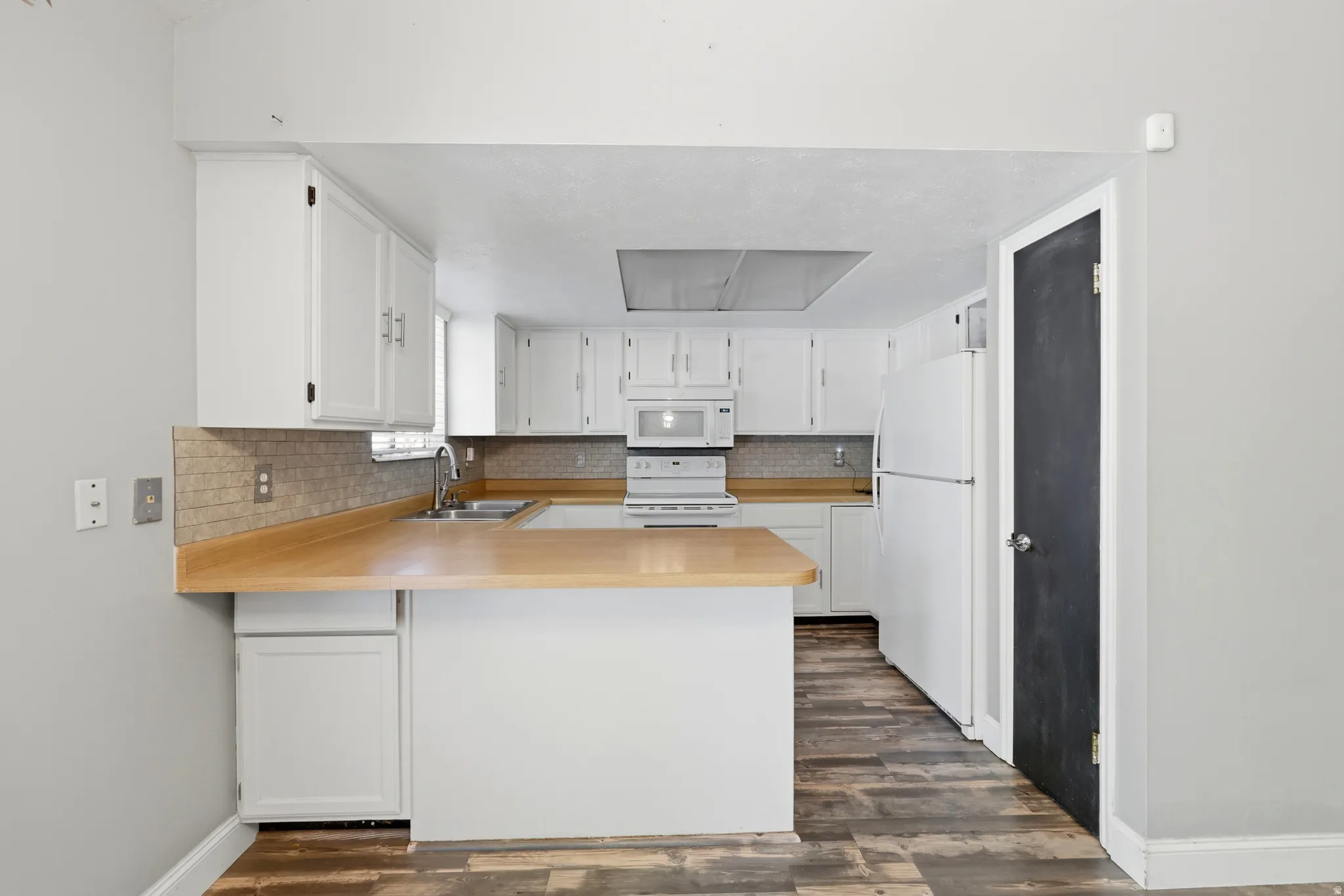 Kitchen featuring wood-finish countertops, white cabinetry, and a tile backsplash