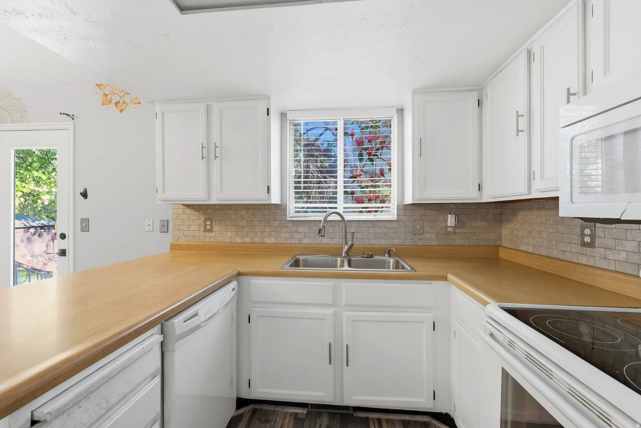 Kitchen featuring white cabinetry, light wood-finish countertops, and a tiled backsplash