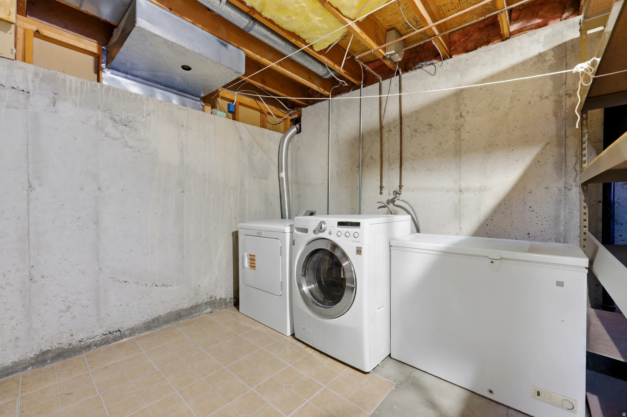 Basement utility area featuring exposed joists, concrete walls, and tile flooring