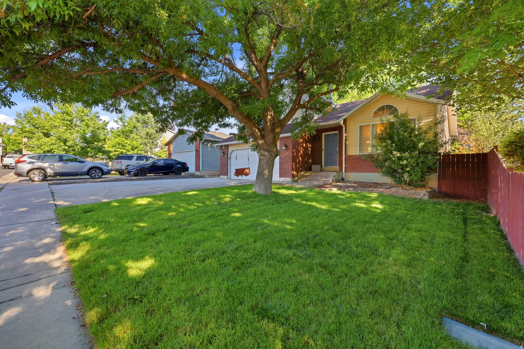 Exterior featuring a mature tree providing shade, a manicured lawn, a detached two-car garage, and a fenced side yard