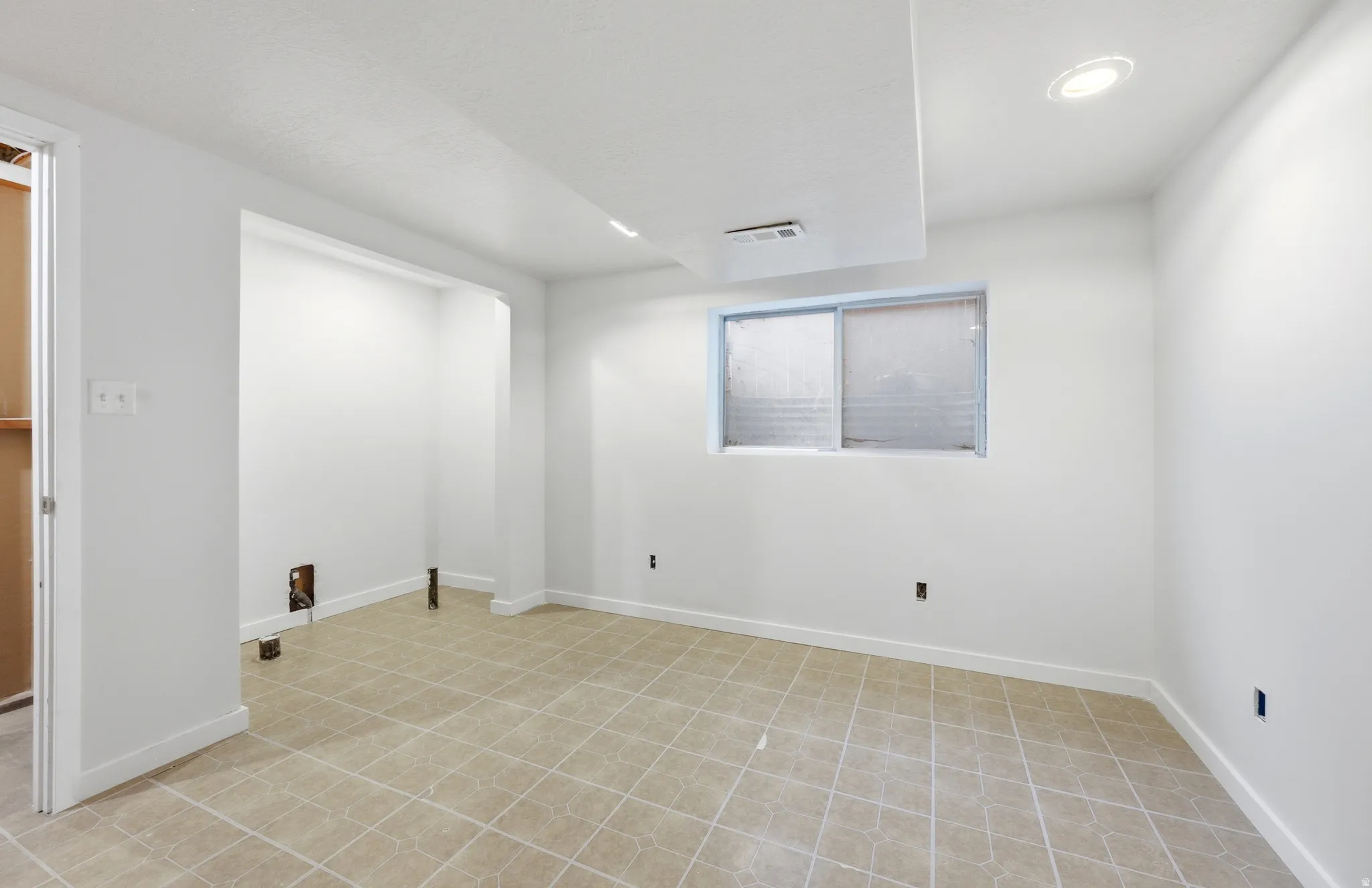 Recessed lighting, white walls, and light-toned tile flooring