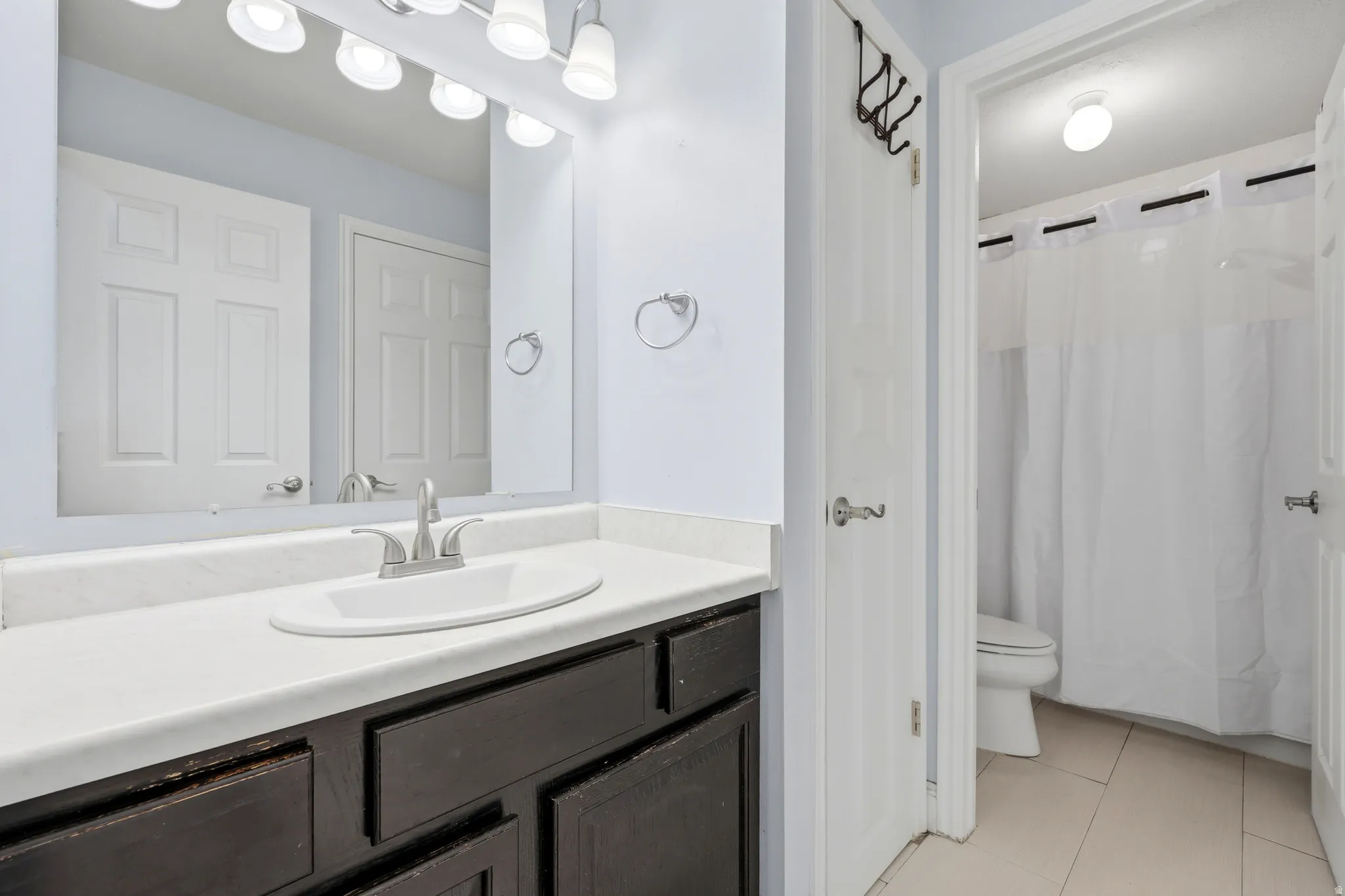 Bathroom vanity featuring a white oval sink, brushed nickel faucet, and dark wood-finish cabinetry