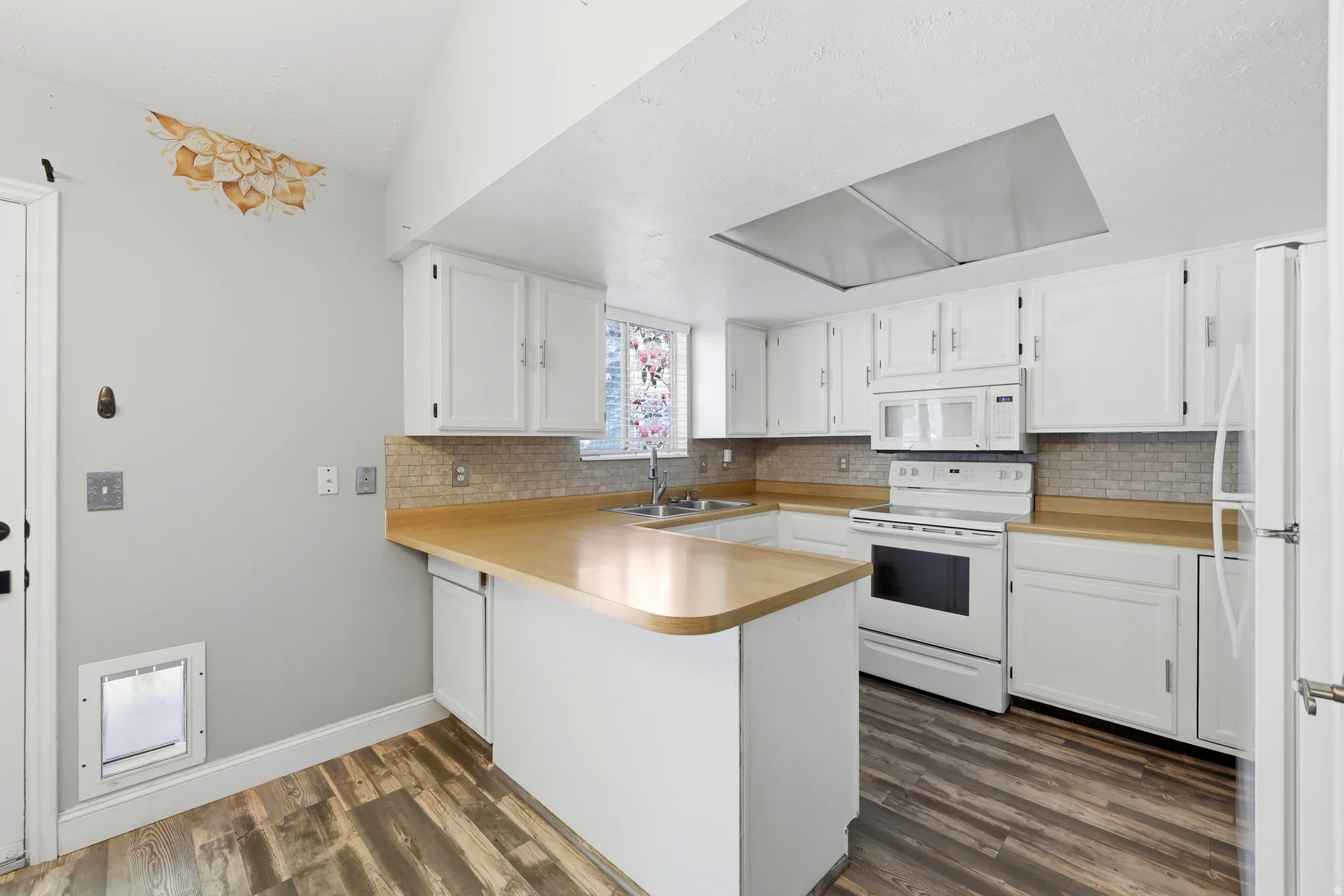 Kitchen featuring white cabinetry, light wood-finish countertops, tile backsplash, and wood-finish flooring