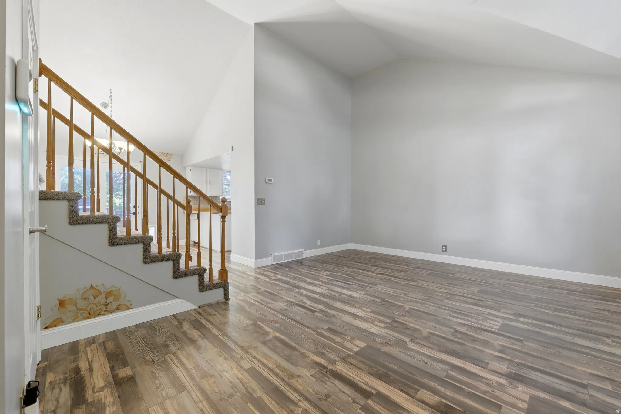 Vaulted ceiling main living area featuring wood-finish flooring and light gray wall paint