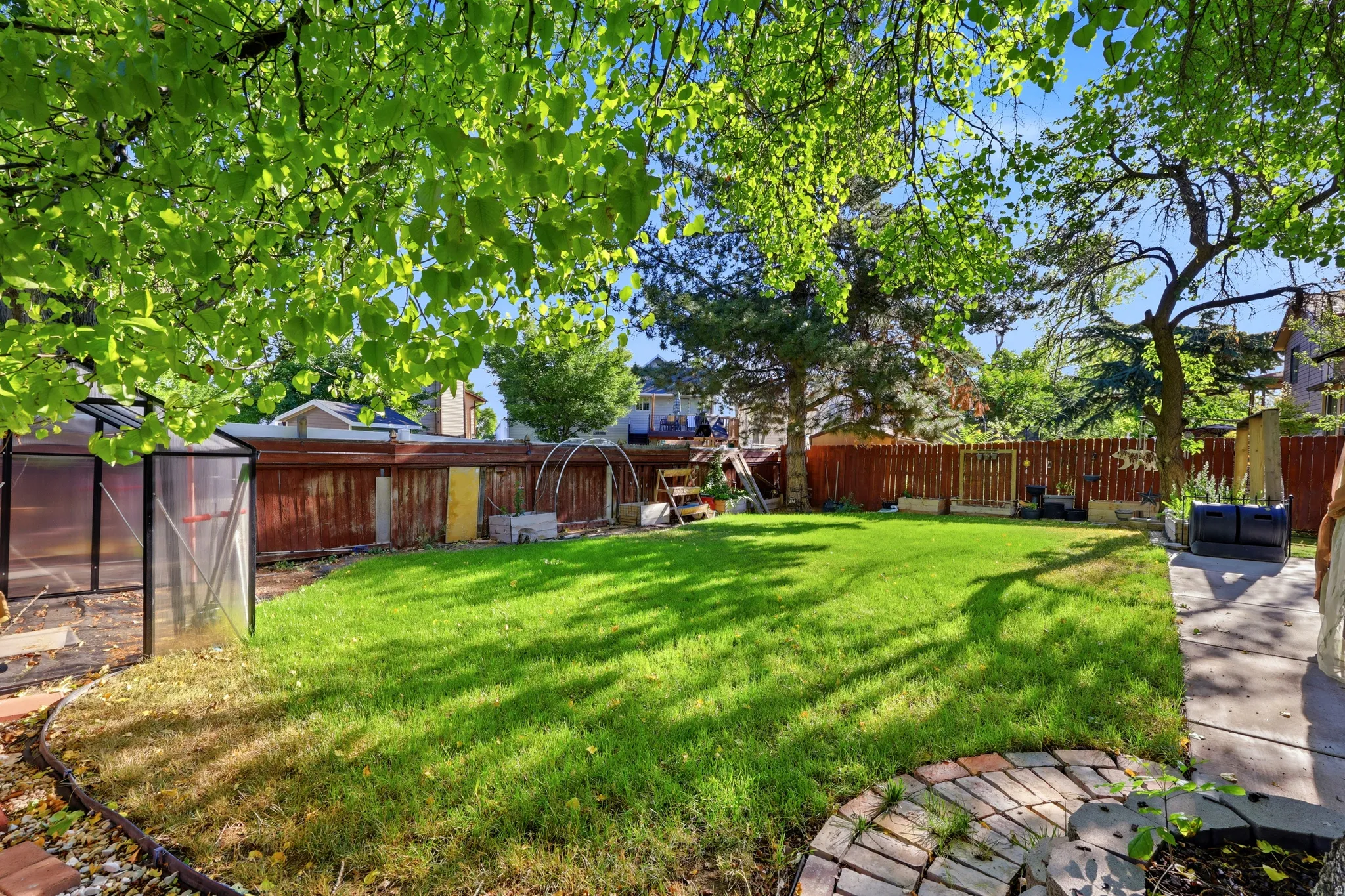 Spacious backyard featuring a manicured lawn, established perimeter trees, and a privacy fence