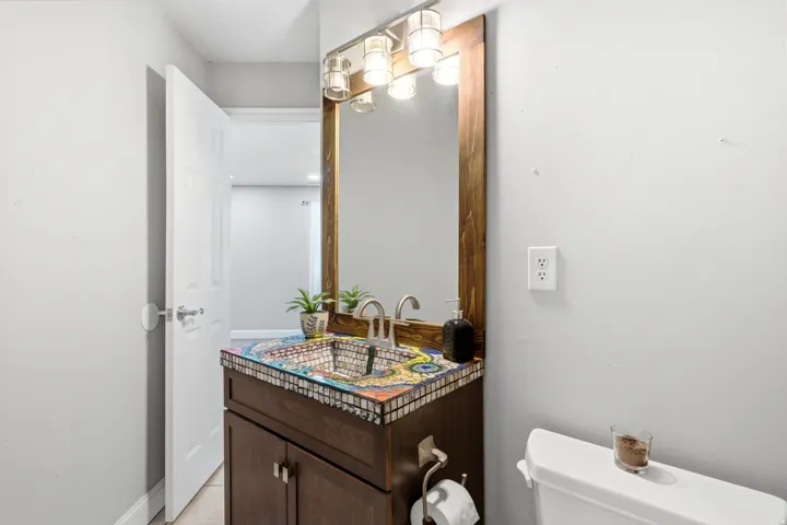 Vanity featuring a unique mosaic countertop, integrated basin, and a wood-framed mirror