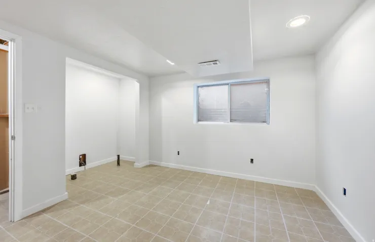 Recessed lighting, white walls, and light-toned tile flooring