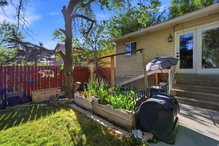 Expansive backyard featuring a wood privacy fence, established trees, and raised garden beds
