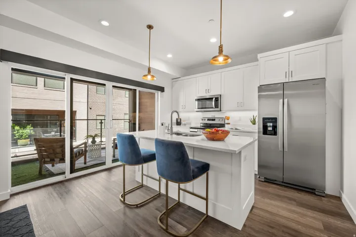 Modern kitchen featuring white cabinetry, stainless steel appliances, a center island with countertop seating, and wood-finish flooring