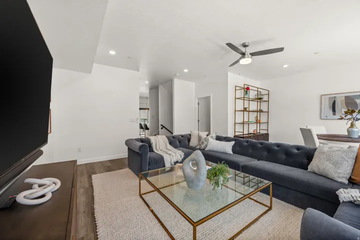 Bright living space featuring wood-finish flooring, recessed lighting, a modern ceiling fan, and a view of a staircase and dining area