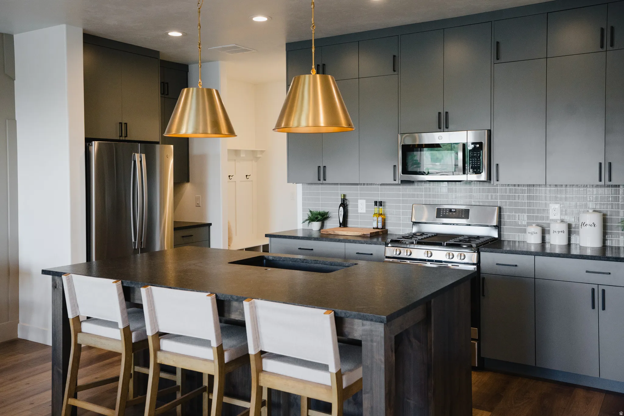 Kitchen featuring an expansive island with an undermount sink, dark cabinetry, and integrated stainless steel appliances
