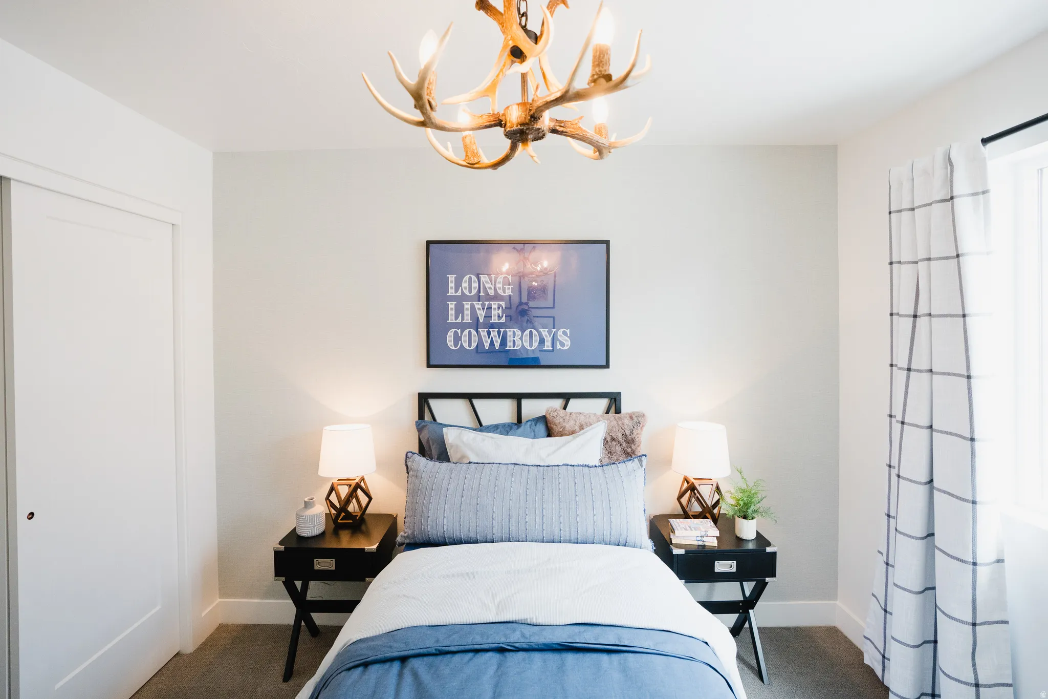 Bedroom featuring a unique antler-inspired chandelier, light gray walls, dark wood-finish nightstands, and a built-in closet with a sliding door