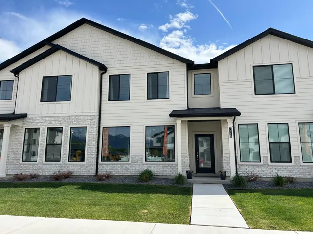Contemporary townhome exterior featuring white vertical and horizontal siding, a black roofline, and contrasting black-framed windows