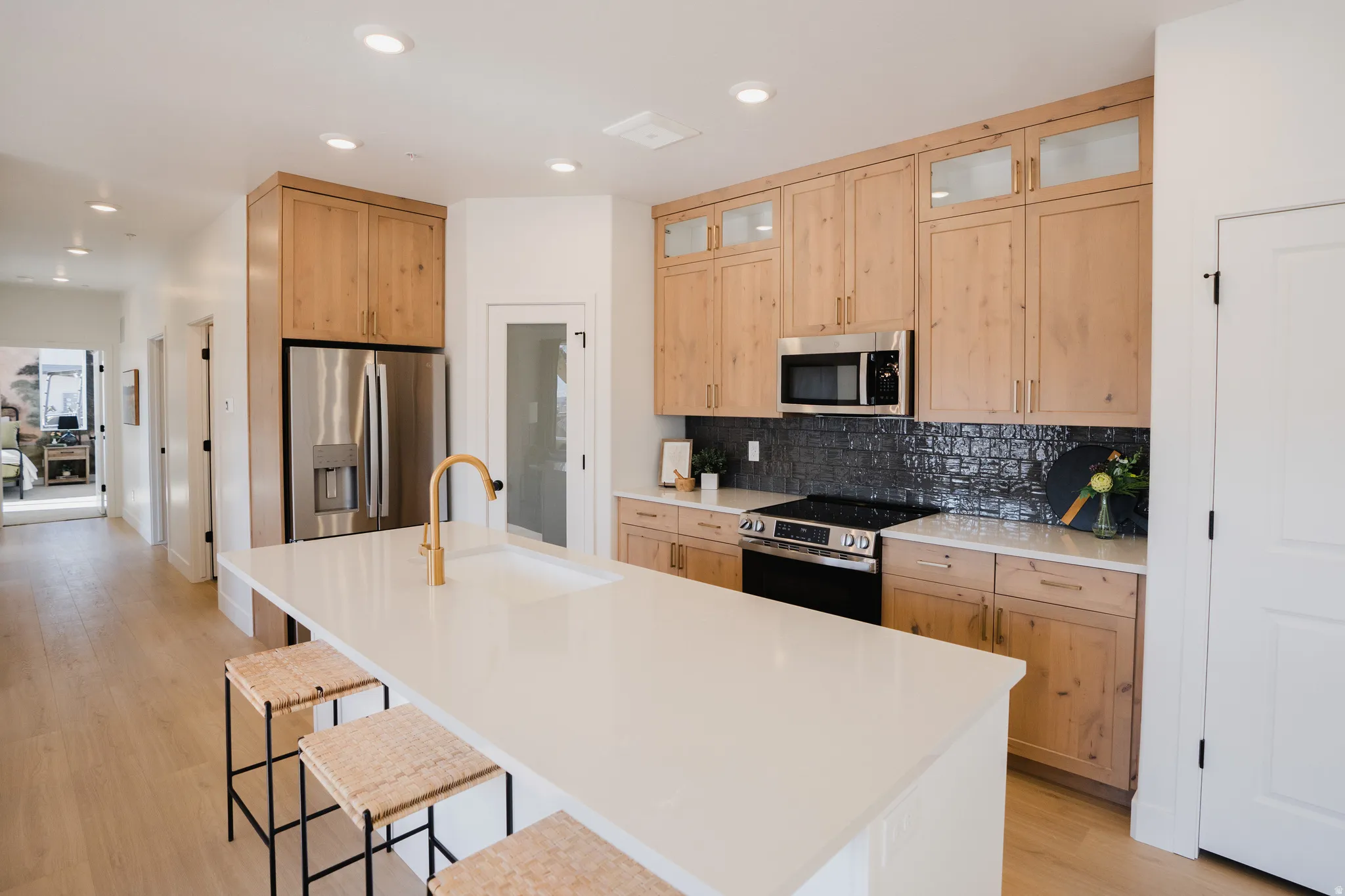 Contemporary kitchen featuring a large center island with an integrated sink and gold-finish faucet