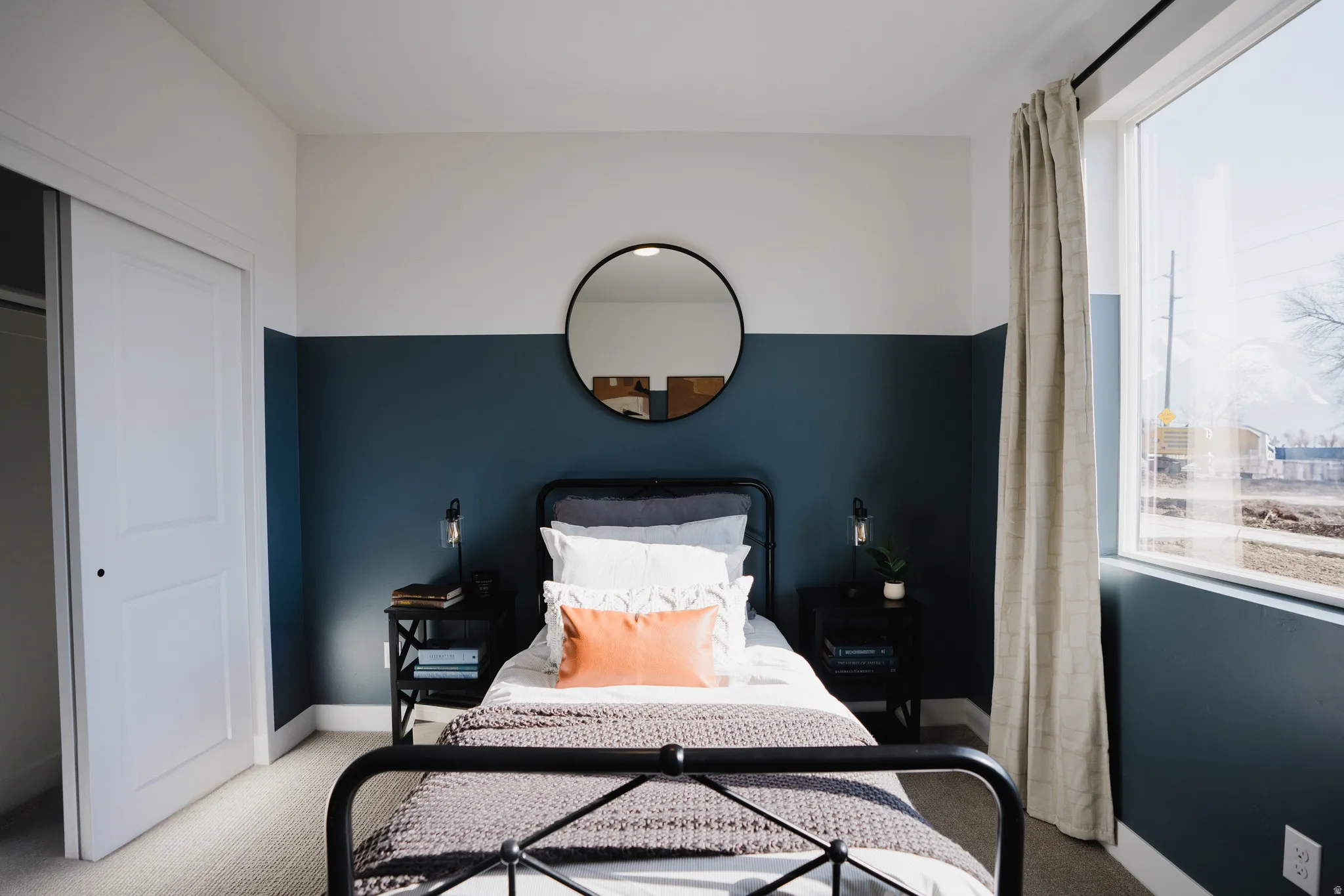 Bedroom featuring a two-tone painted wall, a large window with natural light, and carpeted flooring