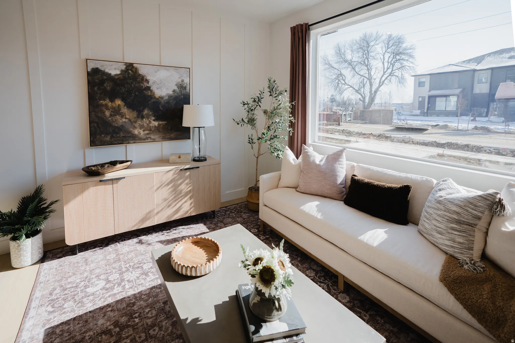 Spacious living area featuring a large picture window, vertical panel accent wall, and wood-finish flooring
