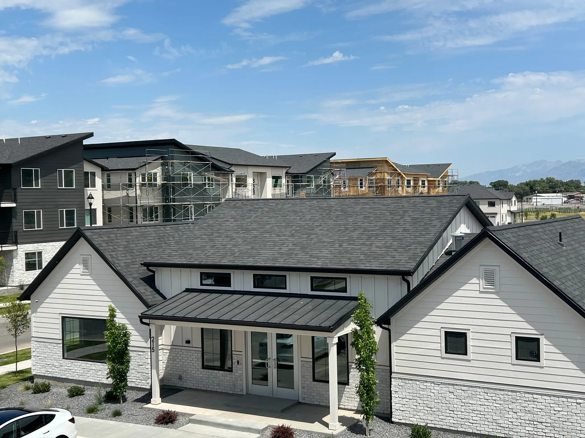 Modern farmhouse style building with contrasting dark gray shingle roofing and white horizontal siding