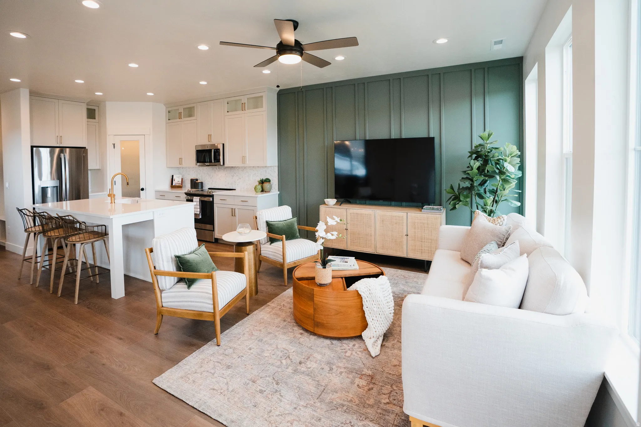 Open-concept living space featuring wood-finish flooring, recessed lighting, and a kitchen island with seating