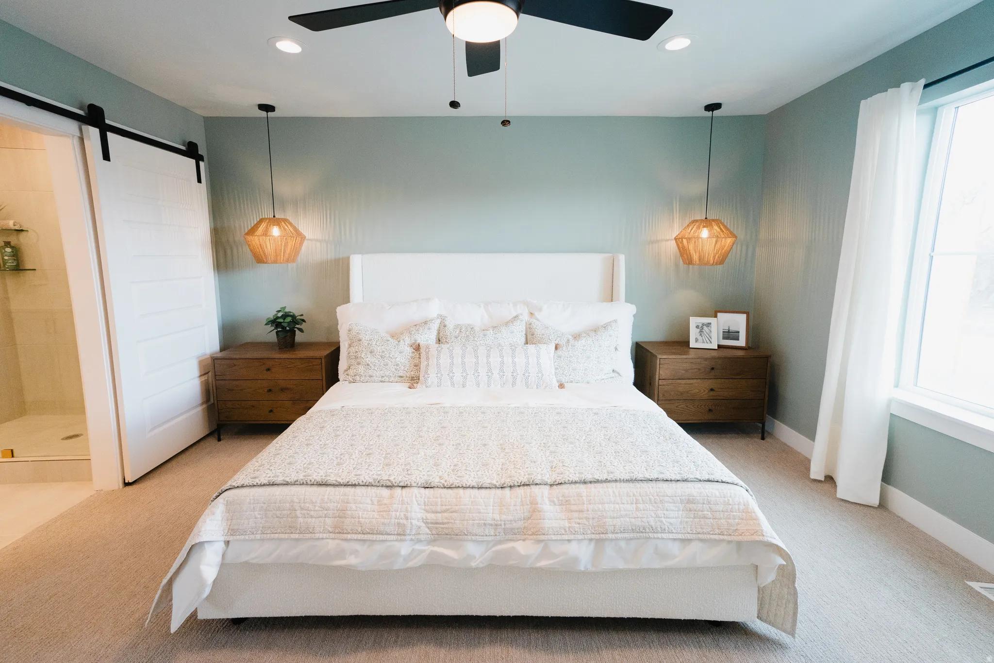 Spacious room featuring a neutral carpet flooring, light blue wall paint, a ceiling fan with integrated lighting, and a window with white trim