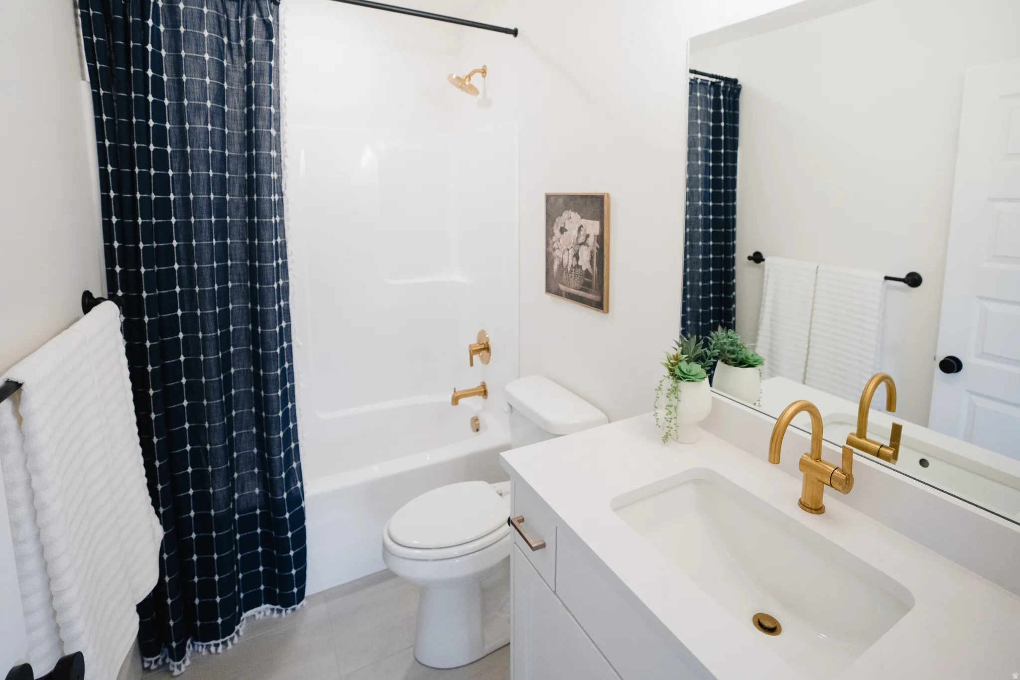 Bathroom featuring a white vanity with integrated sink, gold-finish faucet, and coordinating gold-finish shower fixtures