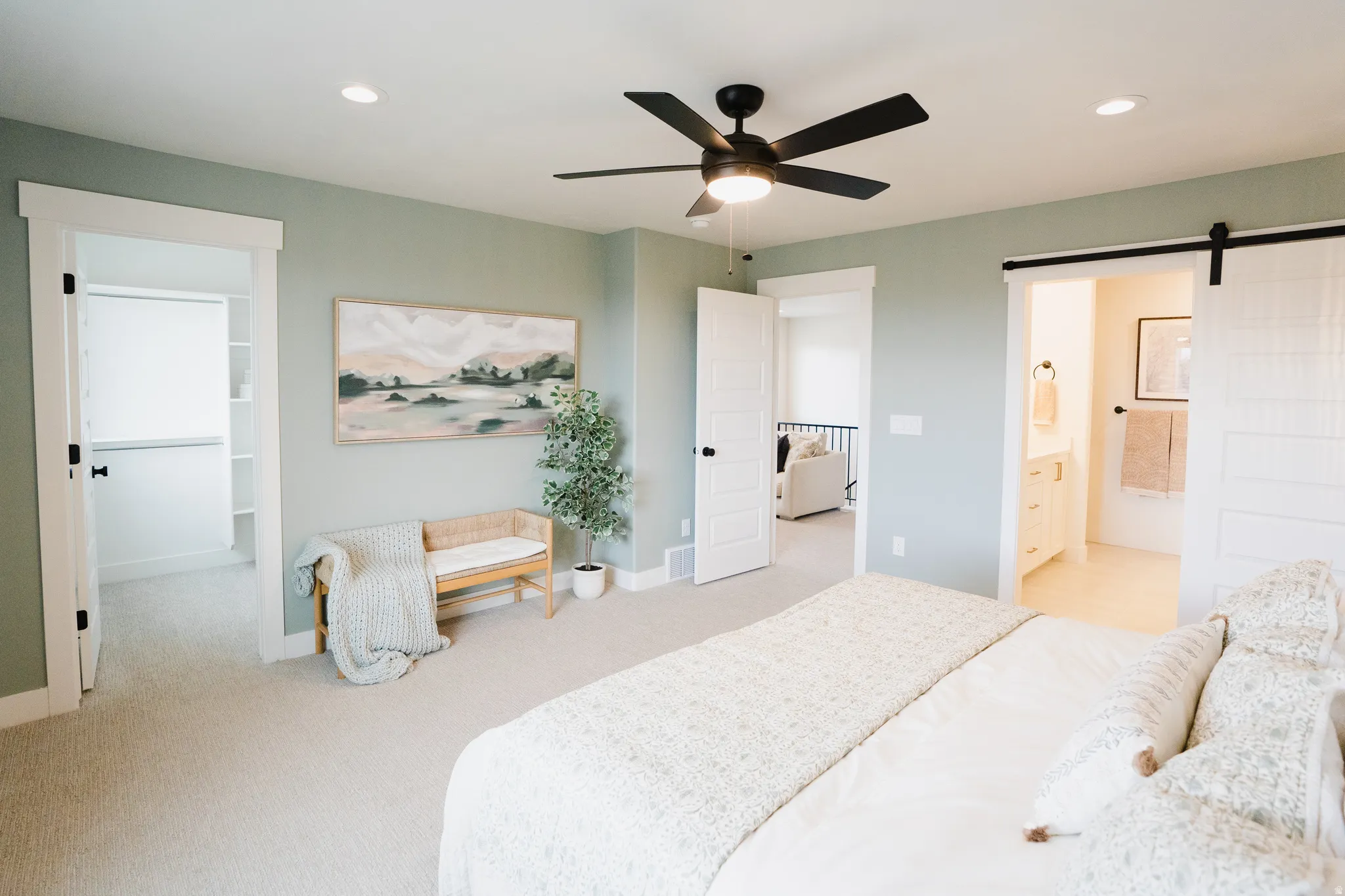 Spacious bedroom featuring light neutral carpeting, a black ceiling fan, and recessed lighting