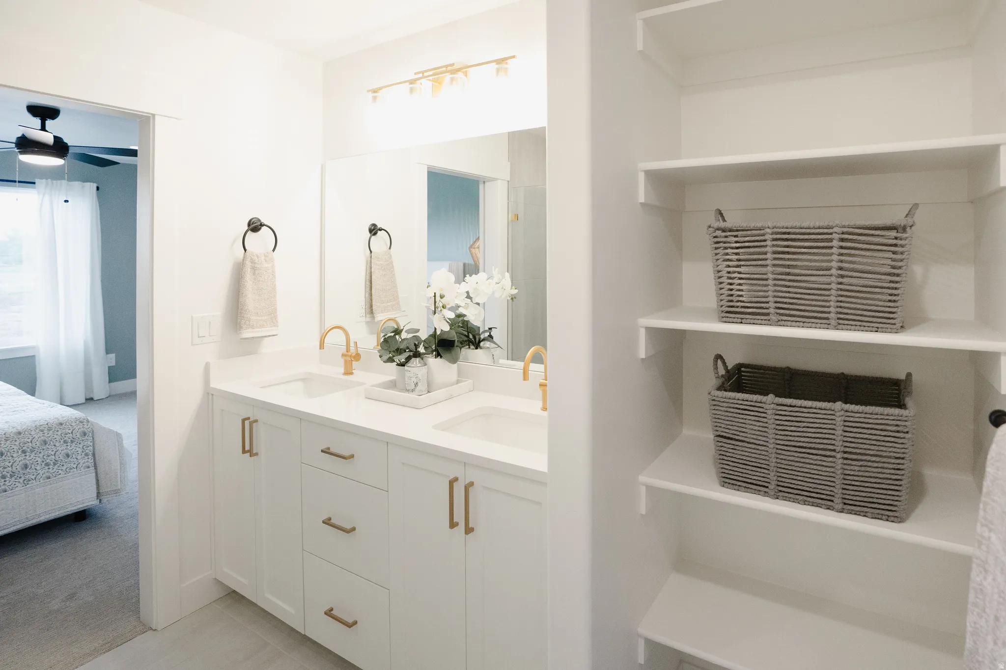 Double vanity featuring white cabinetry, gold-finish hardware, and a light-colored countertop