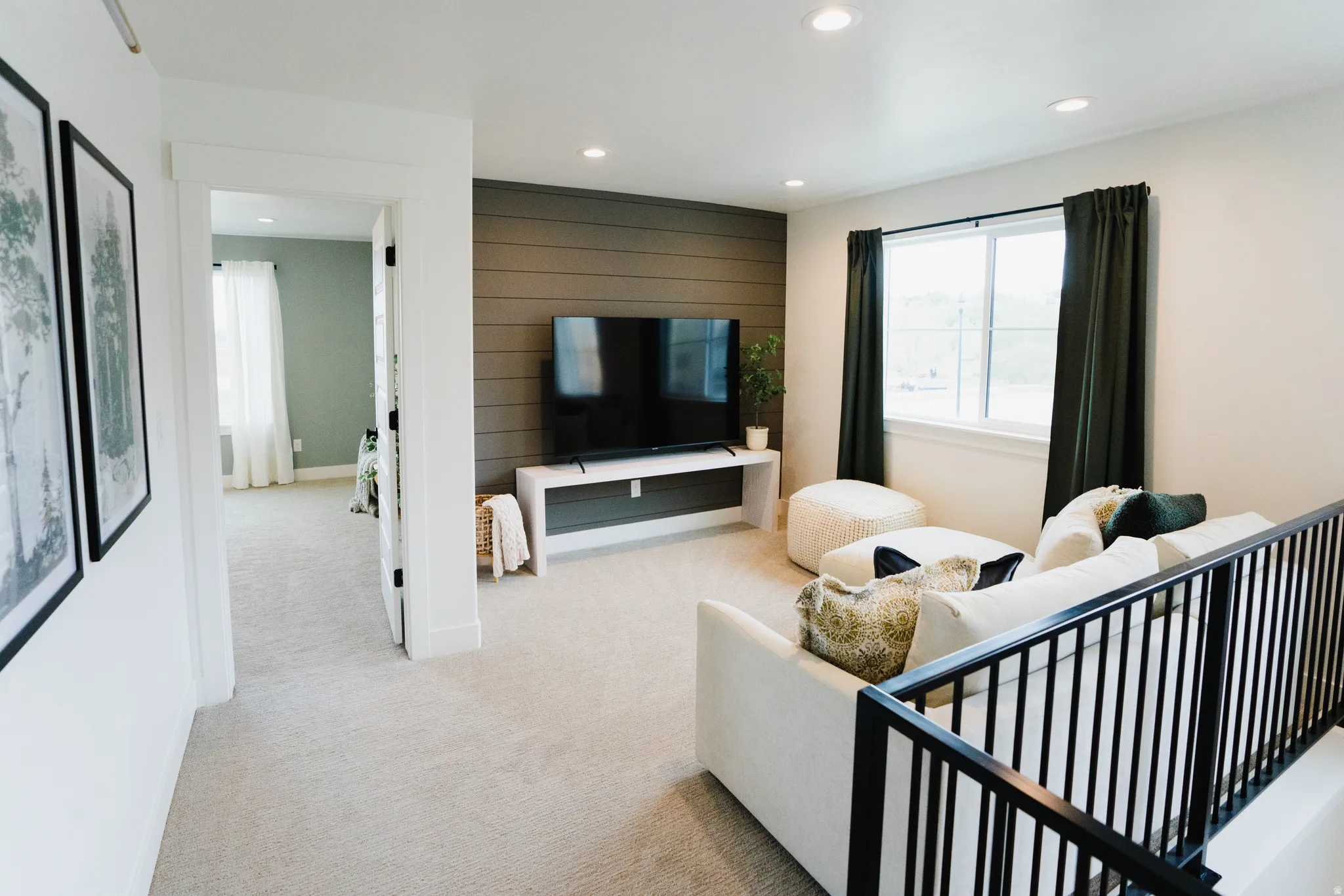 Carpeted open area with shiplap accent wall, white trim, recessed lighting, and a black metal railing