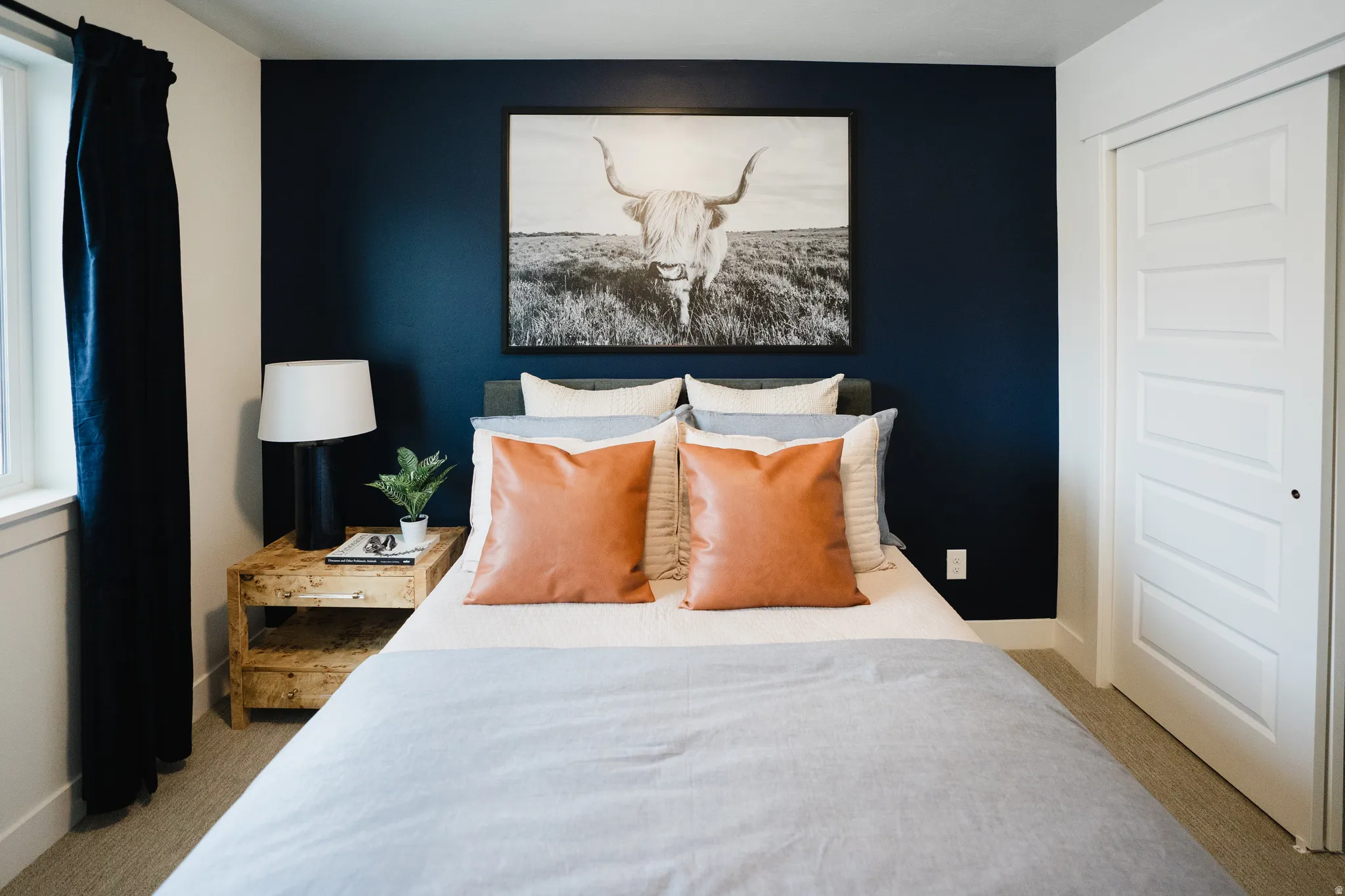 Accent wall with dark blue paint, neutral carpet flooring, and white trim