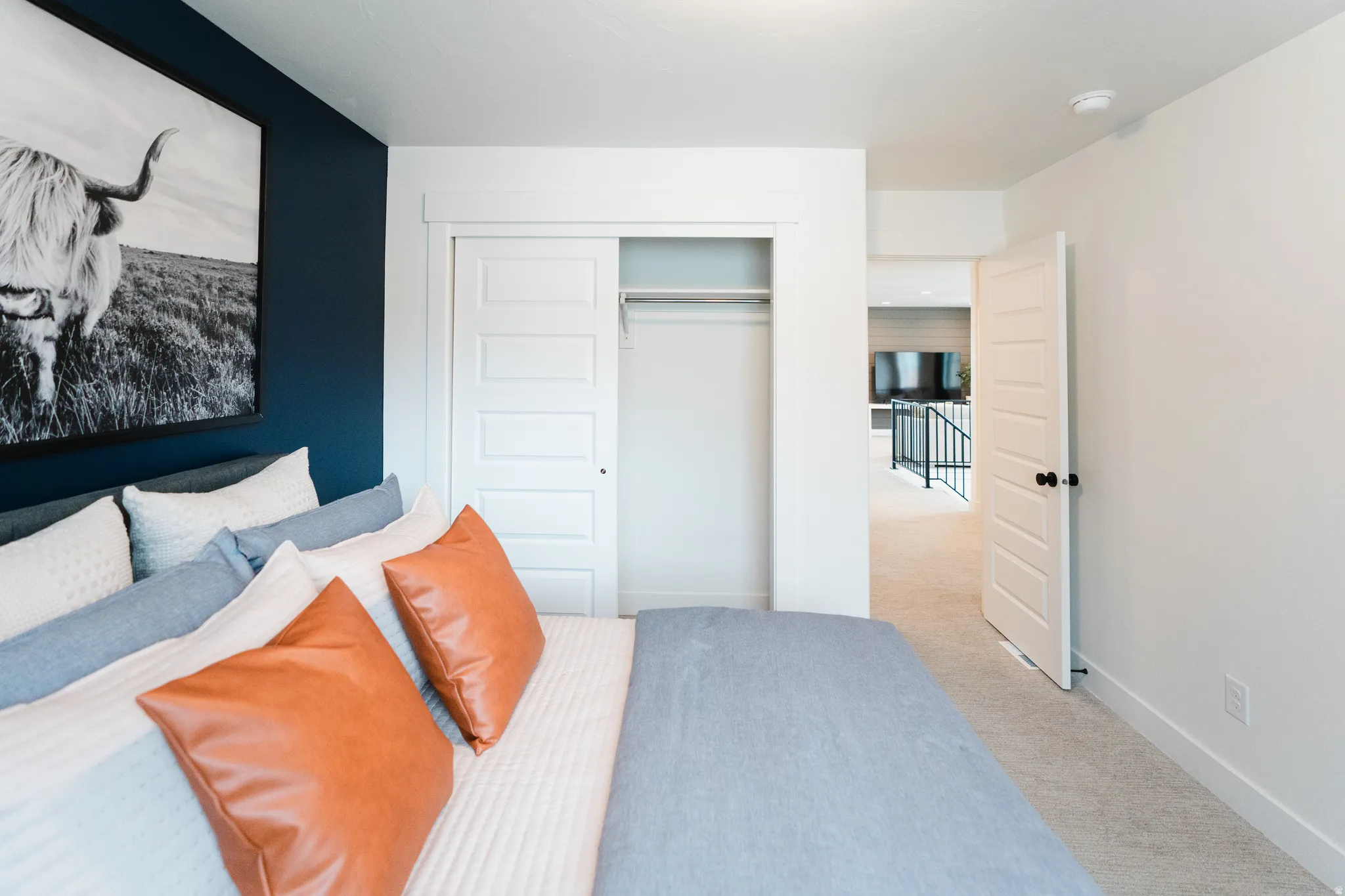 Bedroom featuring a dark accent wall, white trim, and light-colored carpeting